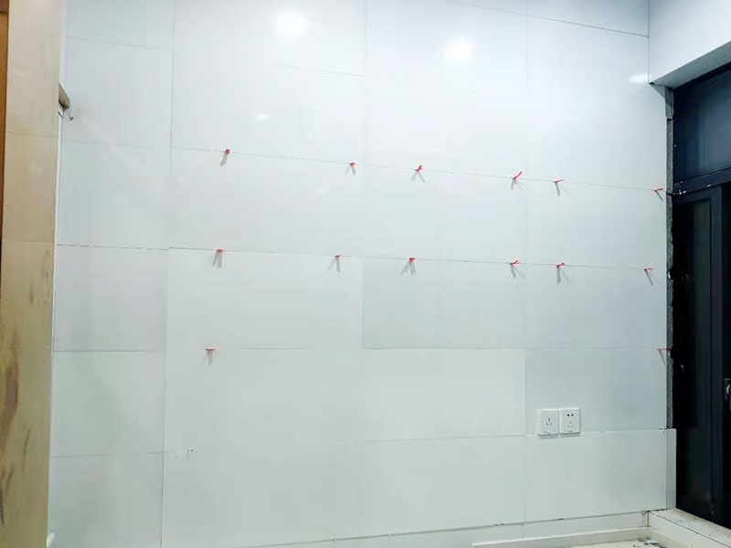 墻磚鋪貼施工：基層處理：保持墻面的平滑，踢平表面凹凸不平的位置或用1:3比例的水泥漿抹平，用鐵絲擦掉殘留的灰塵、油漬、砂漿等。 找標(biāo)高、彈線：根據(jù)水平控制線和設(shè)計圖紙劃出標(biāo)高，再拋出十字線并保持墻面一線和地面一線垂直。 預(yù)鋪：在圖紙設(shè)計要求的基礎(chǔ)上，嚴(yán)格挑選墻磚的色彩、紋理等，然后進行預(yù)鋪，對于預(yù)鋪效果中可能出現(xiàn)的紋理、尺寸、色差進行調(diào)整、更換，直到達(dá)到最佳效果。 貼磚：貼磚選用1：3比例的干硬性水泥砂漿，砂漿厚度2cm左右。鋪貼前將墻磚背面濕潤，正面保持干燥。把墻磚輕輕地放在水泥砂漿上，用手錘輕敲瓷磚表面直至緊密平整即可。 勾縫、擦縫：在貼完磚24小時后進行勾縫工作，采用同一品種的水泥漿或?qū)Ｓ锰羁p劑進行空隙填補，使墻磚最終緊密嚴(yán)實，最后再擦凈多余的水泥或填縫劑。