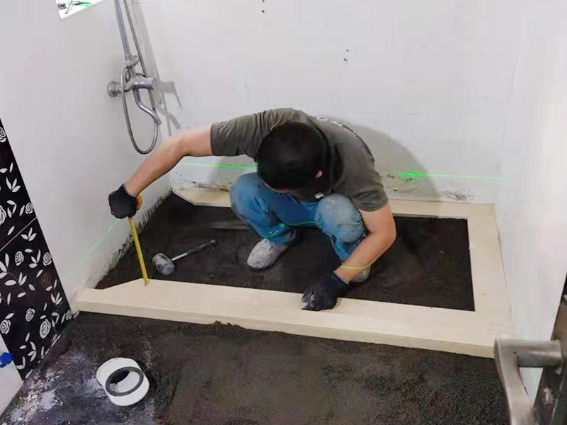 衛生間貼磚施工：應全部清理墻面上的各類污物，打掃干凈現場，特別是腳落里。用泥刀先批墻，后用水泥漿找平。這個工序很重要，確保底子平，防止貼后空鼓。墻面要刷防水涂料，防止貼后浸水，一般高度不低于1.8米，刷的時候會稍高一些。根據設計鋪貼圖樣的要求，確定排磚方案，用墨斗彈線，以減少施工損耗。用鋸齒鏝刀拉槽這點是目前新工藝區別老工藝的一點，使用將粘結劑漿料抹在待鋪貼基層表面，經由鋸齒鏝刀梳理后的條狀漿料飽滿并連續不間斷。瓷磚上墻將經過預先清潔的瓷磚平整地鋪貼在粘結劑漿料基層上，使用橡膠錘將瓷磚拍實鋪平。施工過程中，可小幅度轉動瓷磚，使漿料與瓷磚背面充分接觸。專家建議在鋪貼時，隨機取下已鋪貼于基層上的瓷磚作檢查。確保漿料與瓷磚背面的充分接觸。
